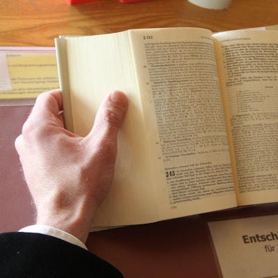 Zwei Hände halten ein aufgeschlagenes Gesetzbuch.