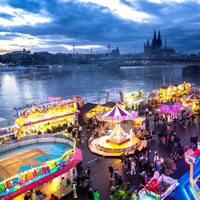 Die Deutzer Kirmes leuchtet in der Abenddämmerung.