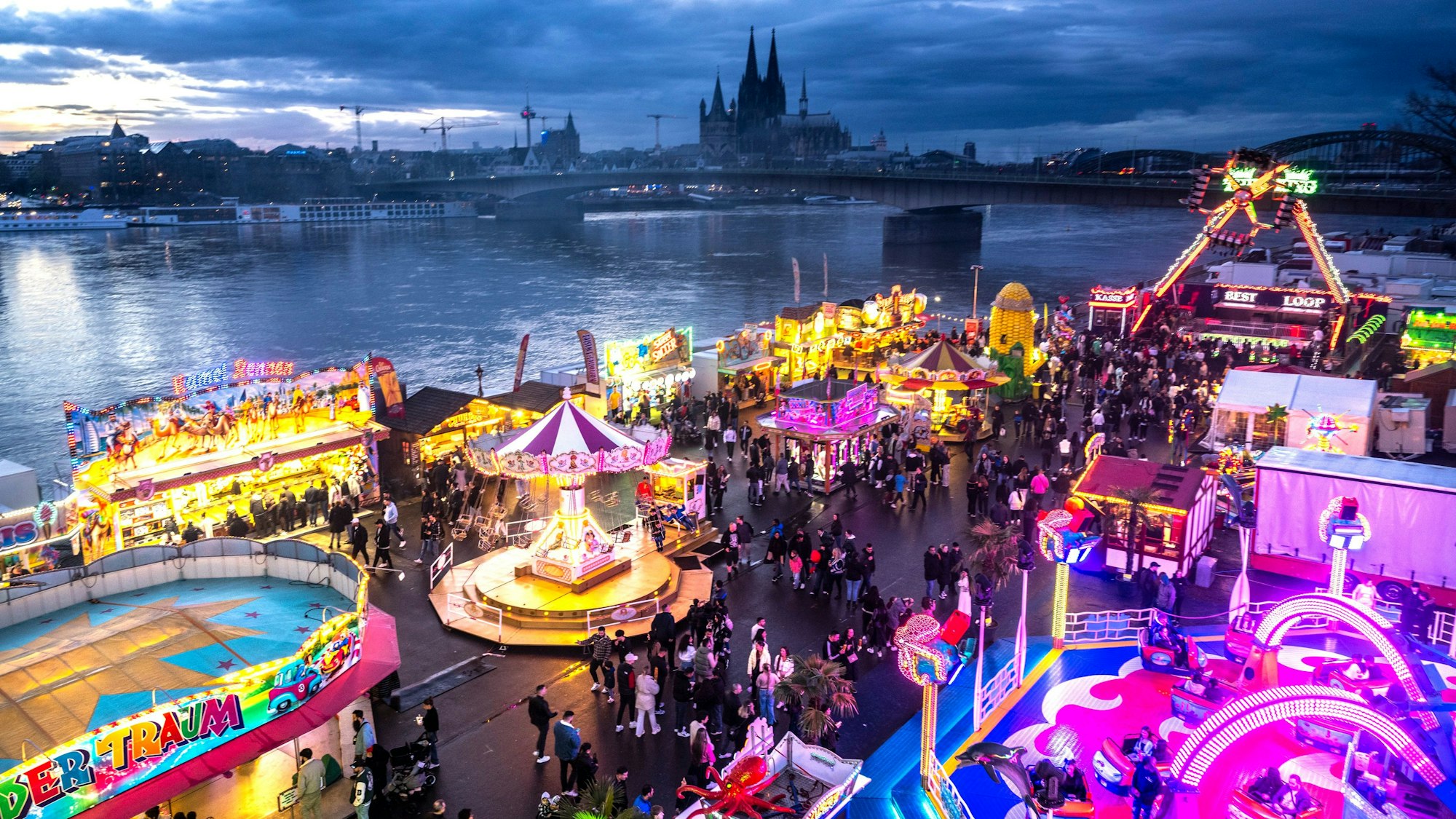 Die Deutzer Kirmes leuchtet in der Abenddämmerung.