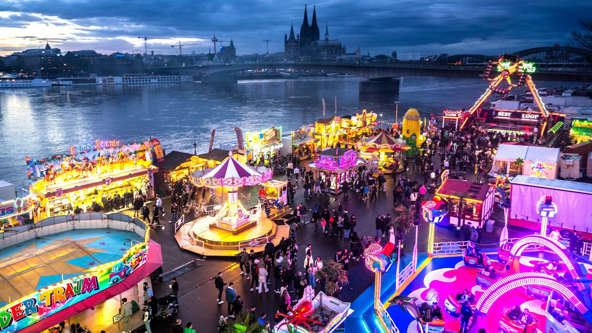Die Deutzer Kirmes leuchtet in der Abenddämmerung.