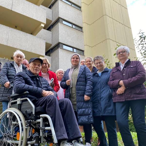 Menschen stehen vor einem Gebäude.
