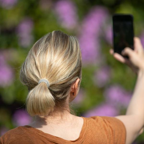 Eine Frau hält ein Smartphone in der Hand und macht ein Selfie.