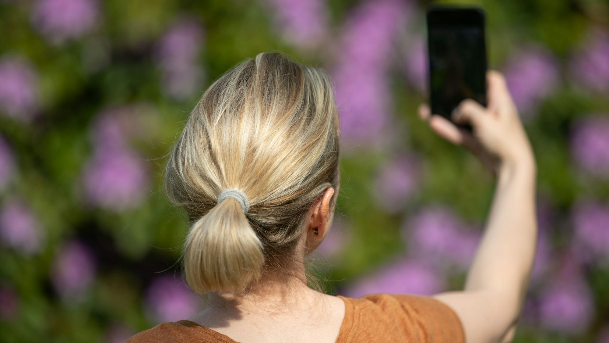Eine Frau hält ein Smartphone in der Hand und macht ein Selfie.