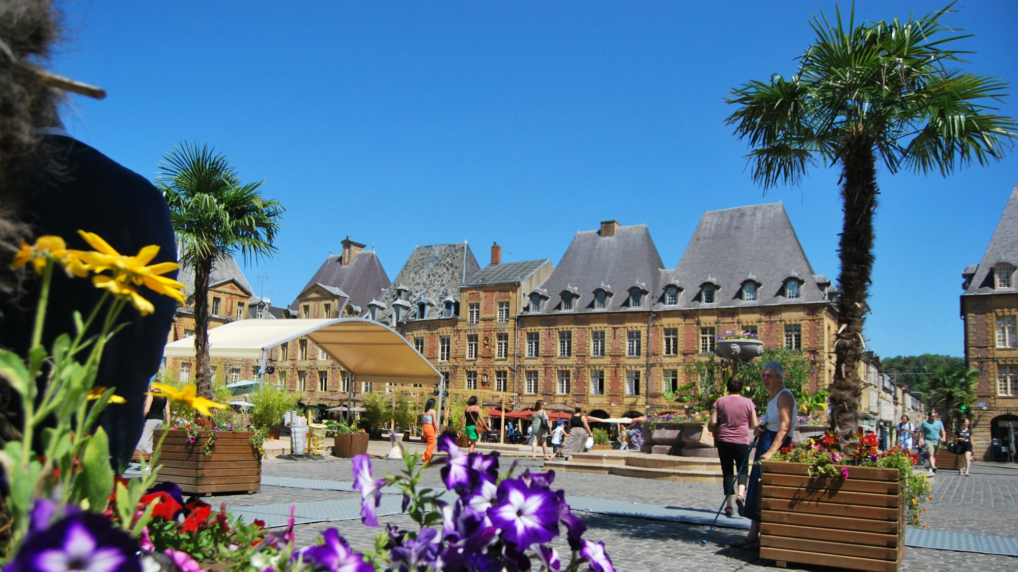 Der Platz ist umgeben von Häusern im Barockstil, im Vordergrund Blumen.