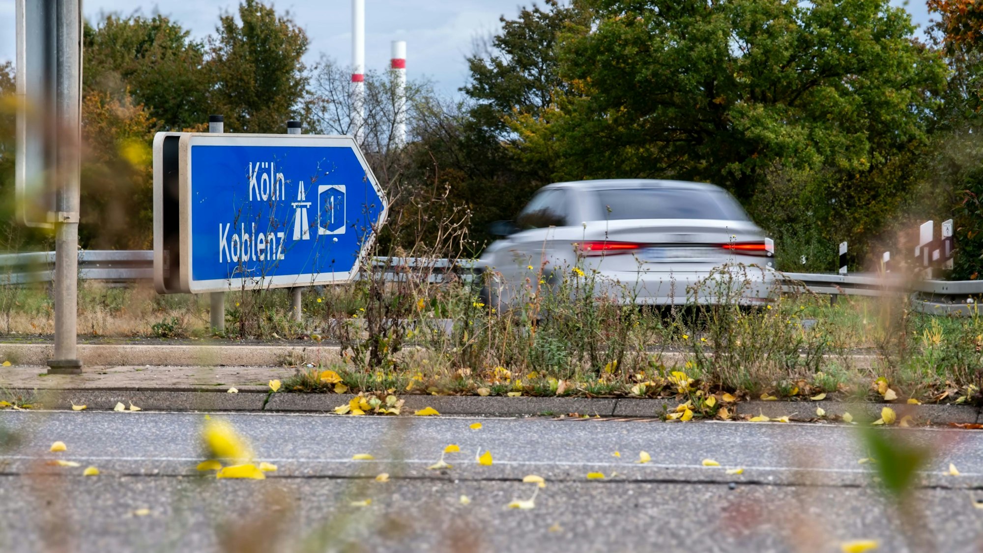 Ein Schild weist auf die Autobahn in Richtung Köln, ein Wagen biegt in die Richtung ab.