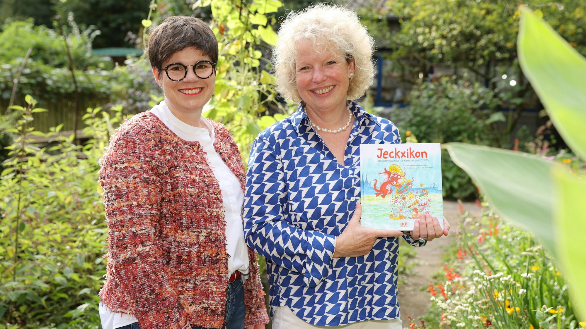 Brigitte Hintzen-Bohlen und Christine Flock mit einem Buch in einem Garten.