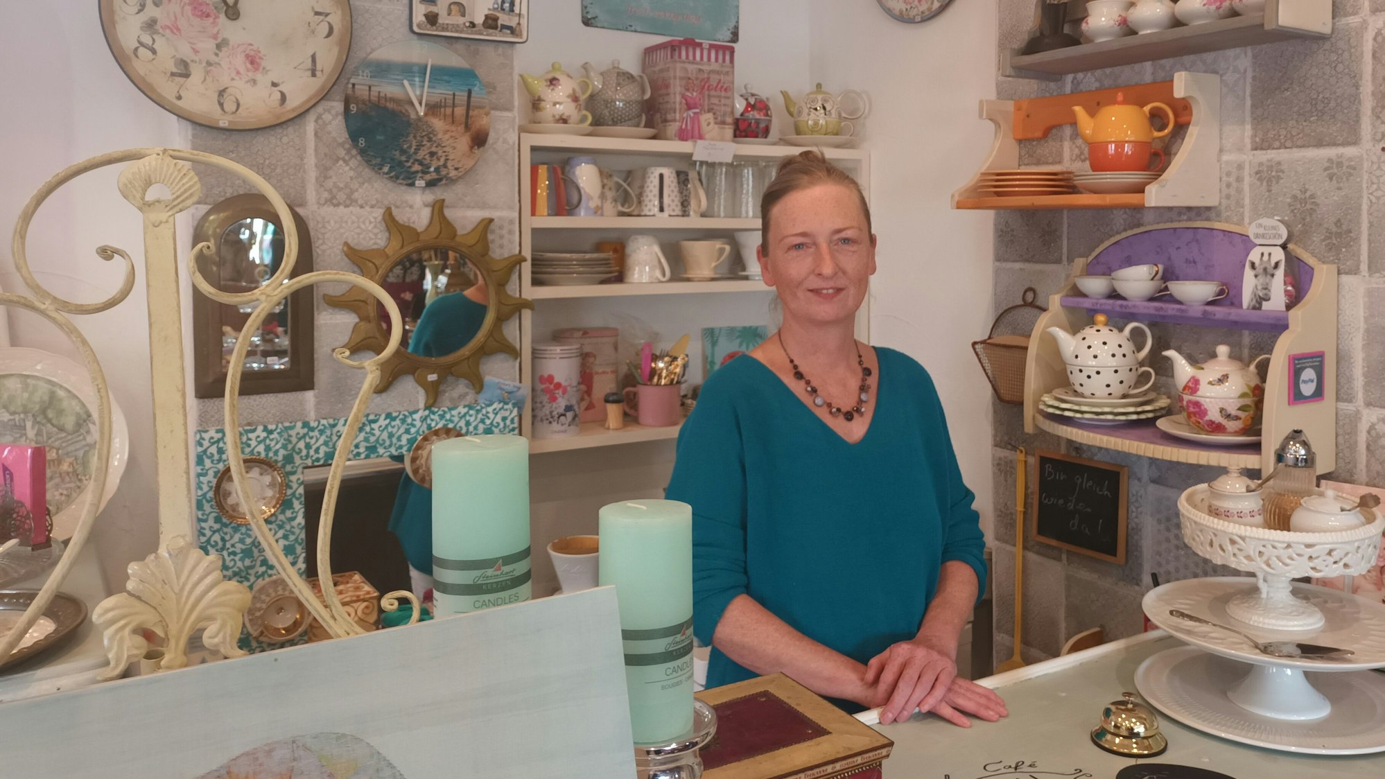 Eine Frau steht hinter einer mit Antiquitäten dekorierten Theke