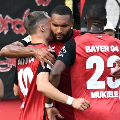 Bayer Leverkusens Jonathan Tah (M) mit Florian Wirtz (L) und Nordi Mukiele.