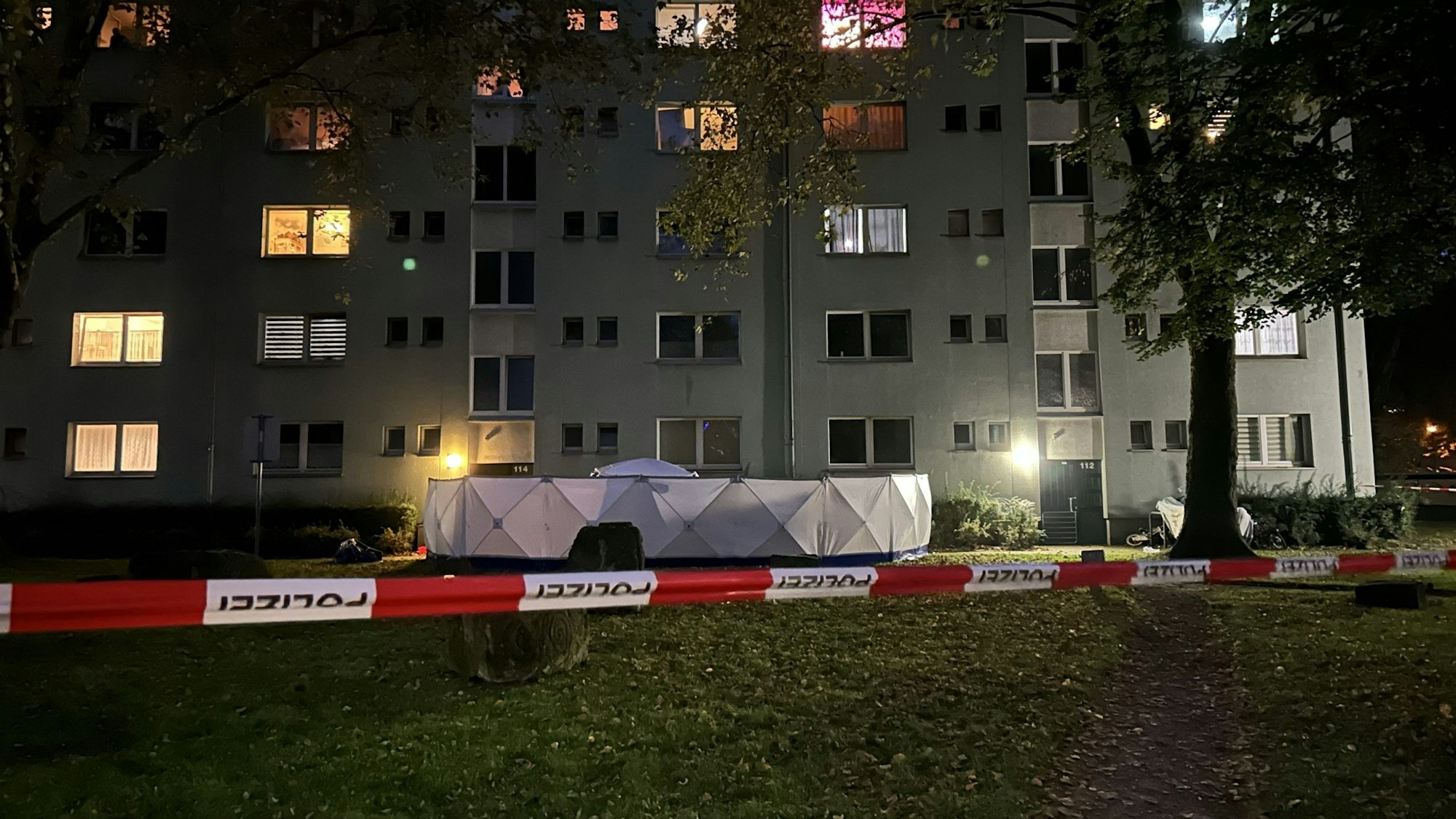 Flatterband und weißer Sichtschutz vor Mehrfamilienhaus, wo eine Frau getötet wurde
