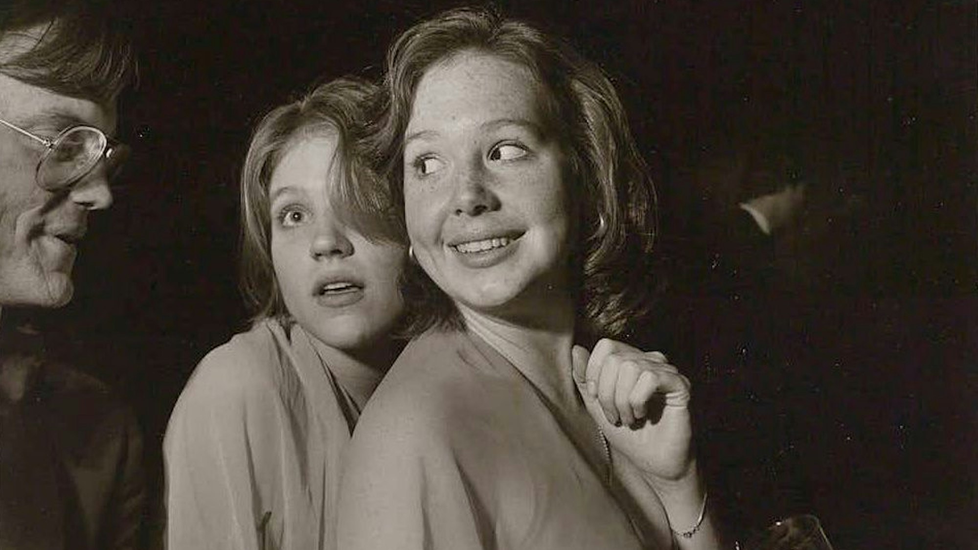 Zwei junge Frauen sprechen mit einem älteren Mann.