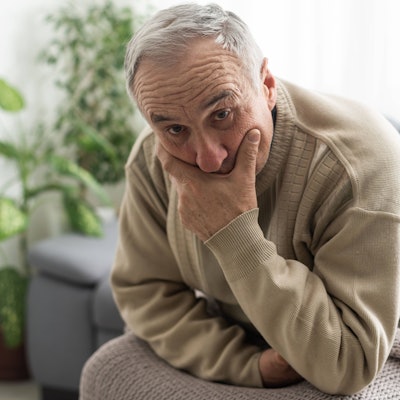 Ein alter Mann denkt nachdenklich auf seinem Sofa.