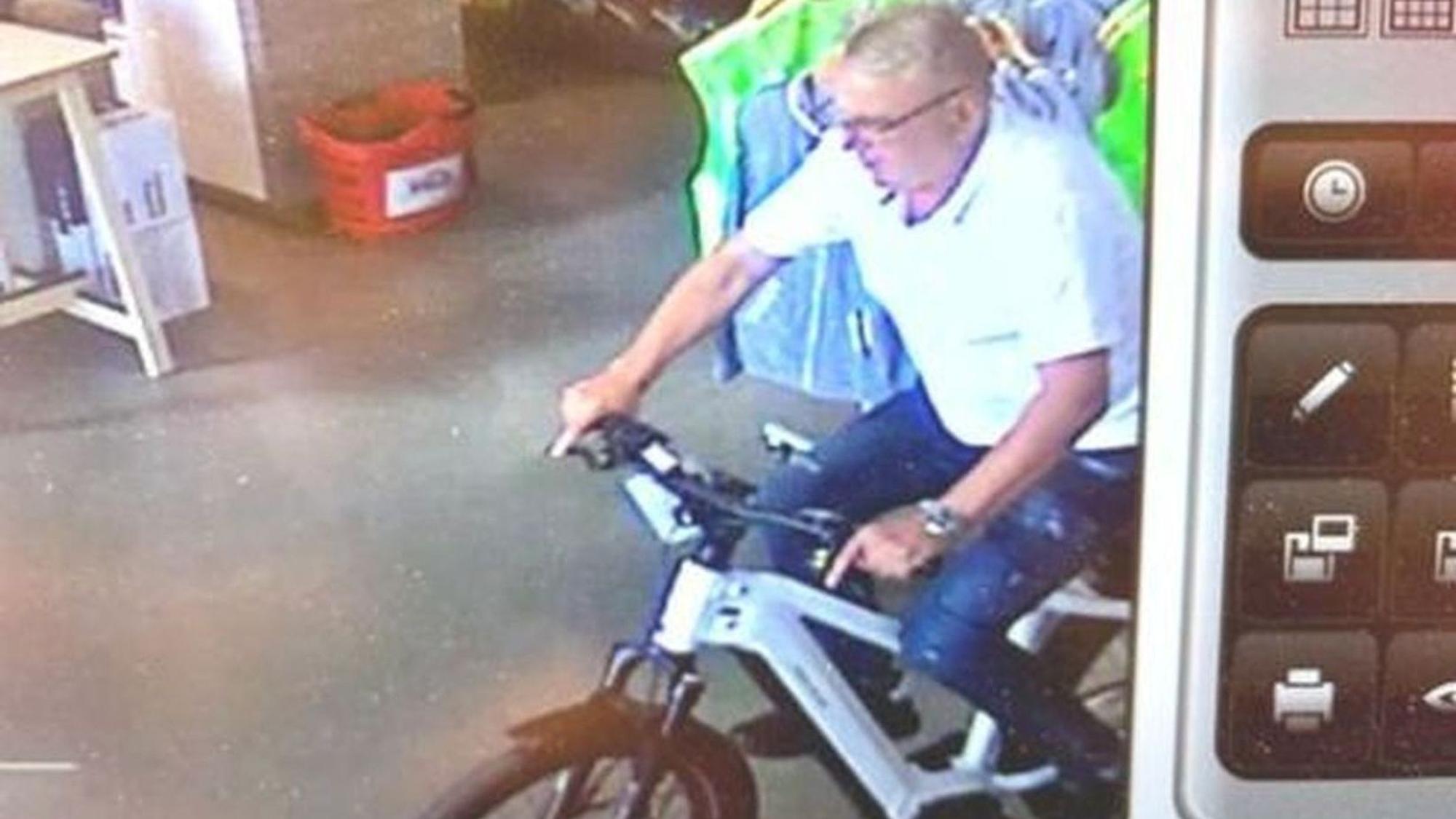 Ein Unbekannter fährt mit einem E-Bike aus einem Fahrradladen.