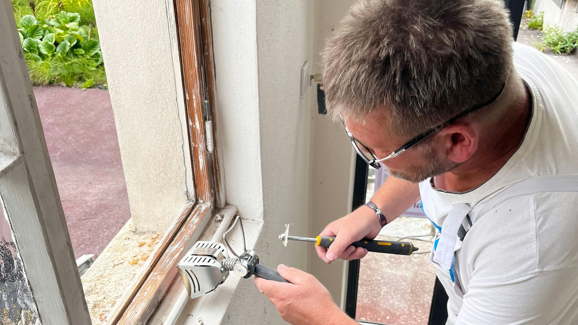 Malermeister Dirk Pabst arbeitet an einem alten Fensterrahmen.