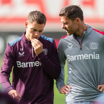 Leverkusens Trainer Xabi Alonso (r) unterhält sich mit Florian Wirtz.