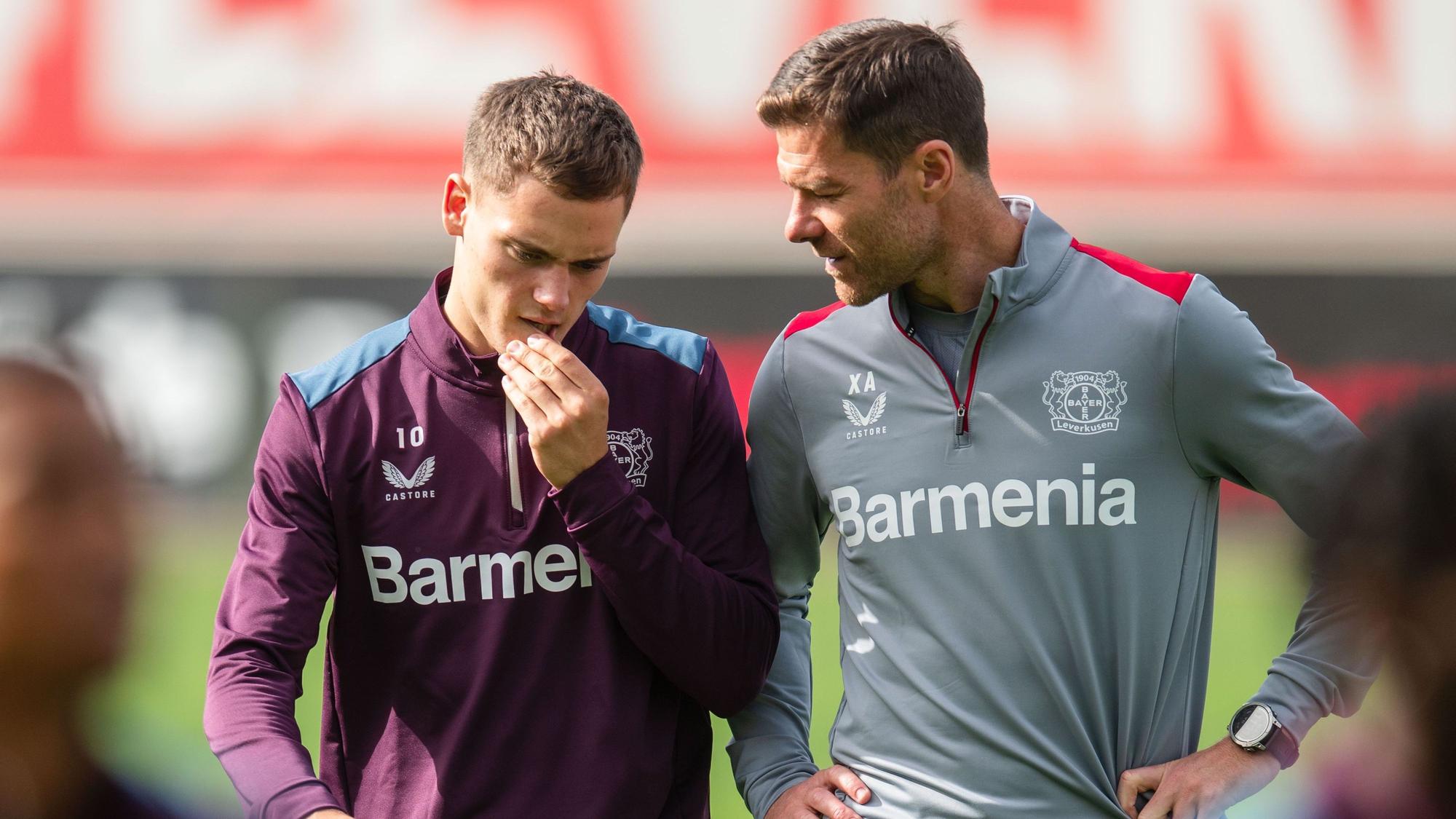 Leverkusens Trainer Xabi Alonso (r) unterhält sich mit Florian Wirtz.