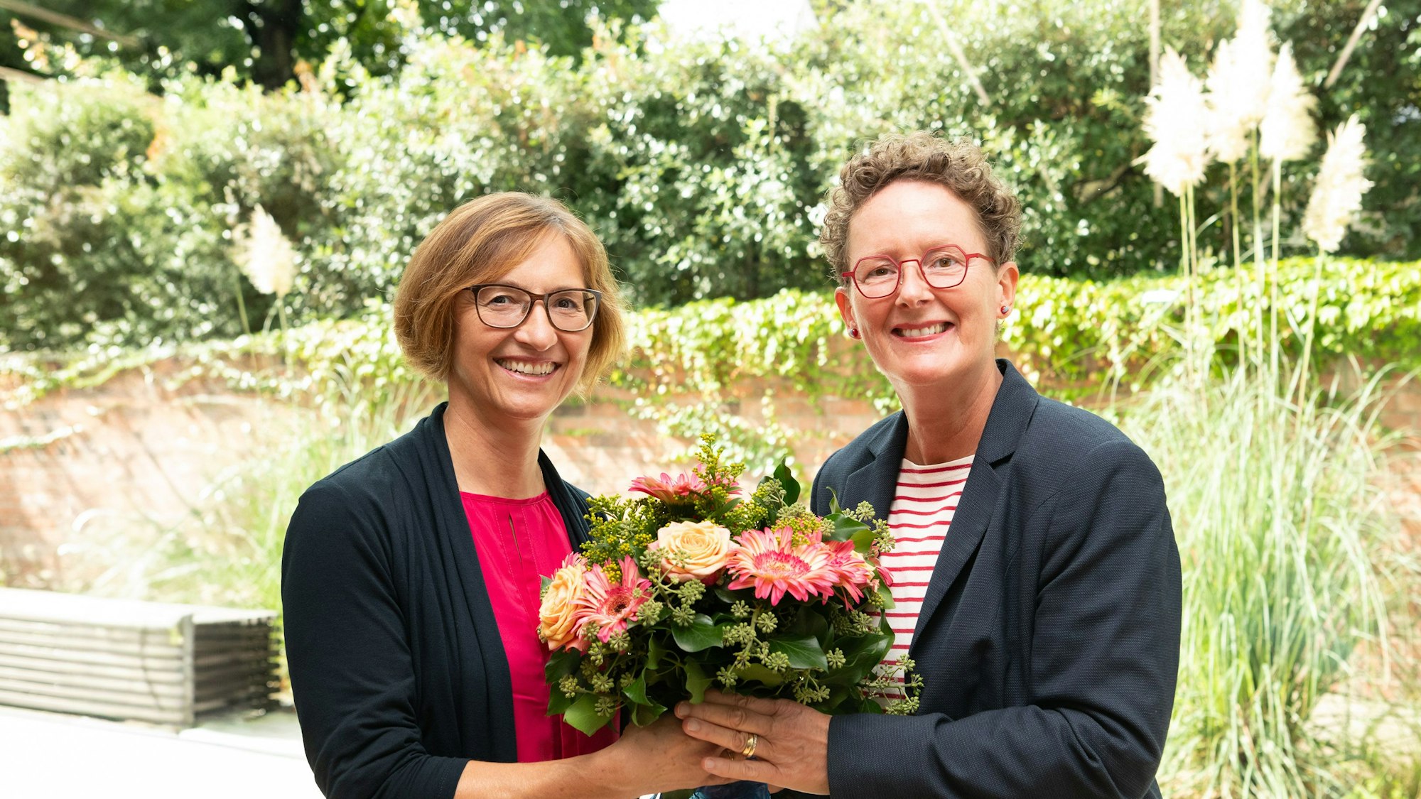 Gratulation mit Blumenstrauß: Barbara Schermaier-Stöckl (l.), Rektorin der Katholischen Hochschule, und Professorin Sabine Hartmann-Dörpinghaus, die den Studiengang leitet und mit aufgebaut hat.