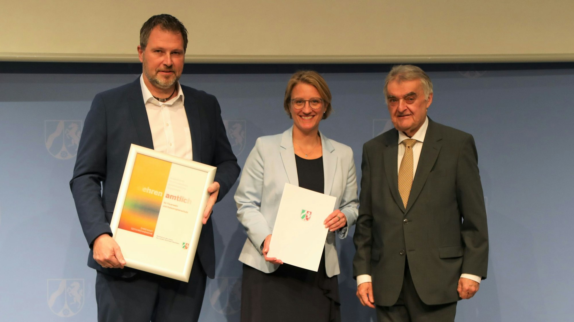 Minister Herbert Reul überreicht eine Förderplakette an die Kampf-Vertreter Markus Vollmer und Rike Svea Johnsen.