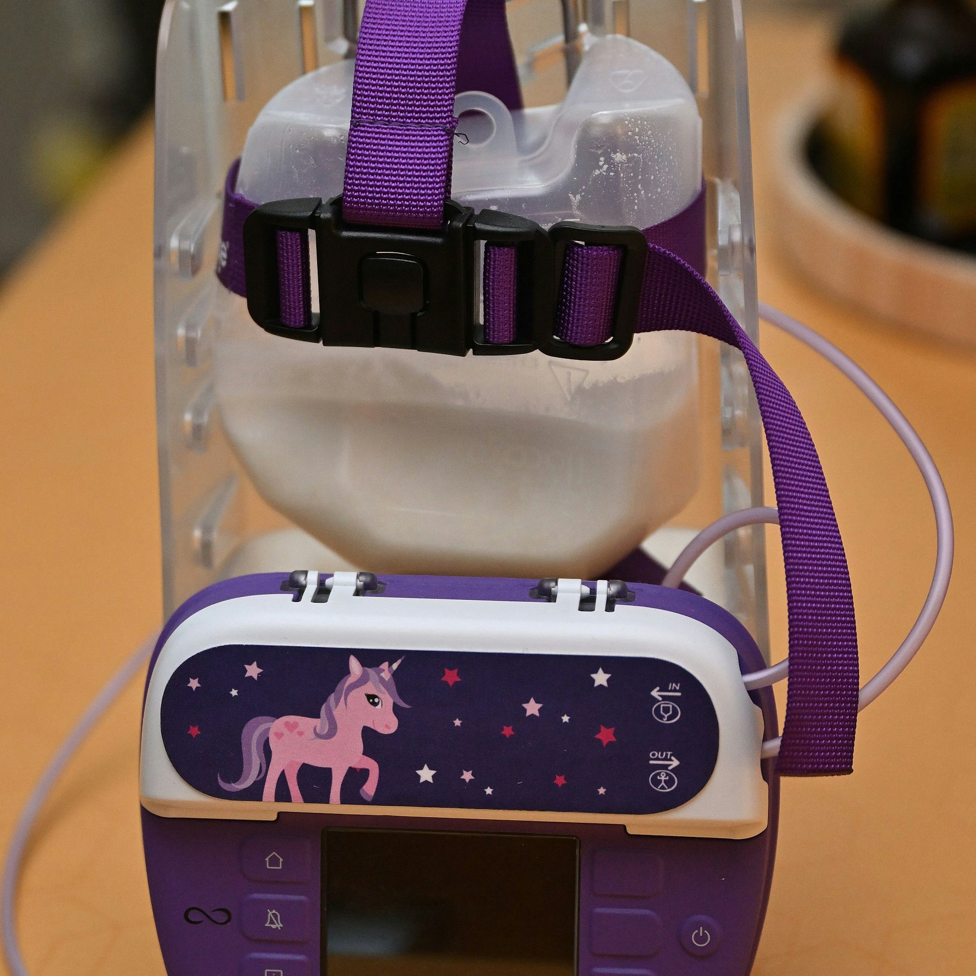 Aus einem Gerät, auf dem ein Einhorn zu sehen und das mit weißer Flüssigkeit gefüllt ist, hängen Schöäuche.