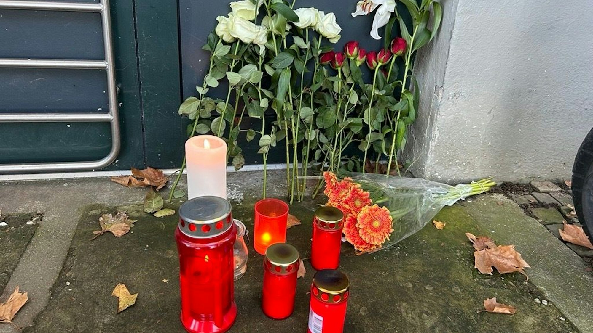 Vor der Haustür des Mehrfamilienhauses haben Anwohner Blumen und Kerzen abgelegt.