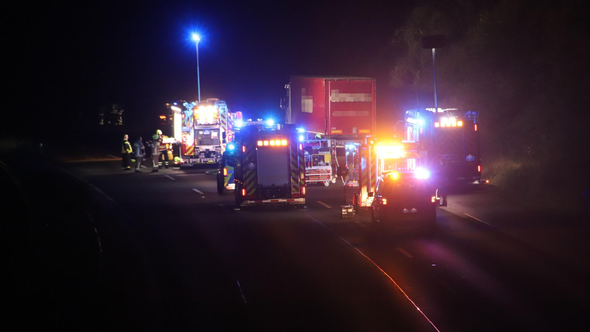Feuerwehrautos stehen hinter und neben einem Lastwagen.