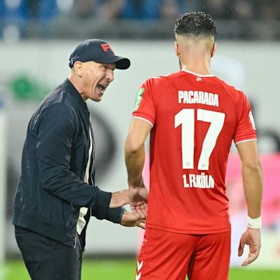 Kölns Trainer Gerhard Struber (l) spricht mit Kölns Leart Paqarada.