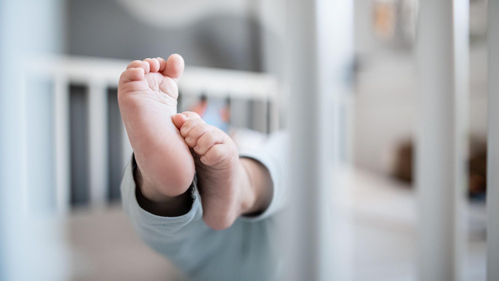 Füße eines Babys in einem Beistellbett