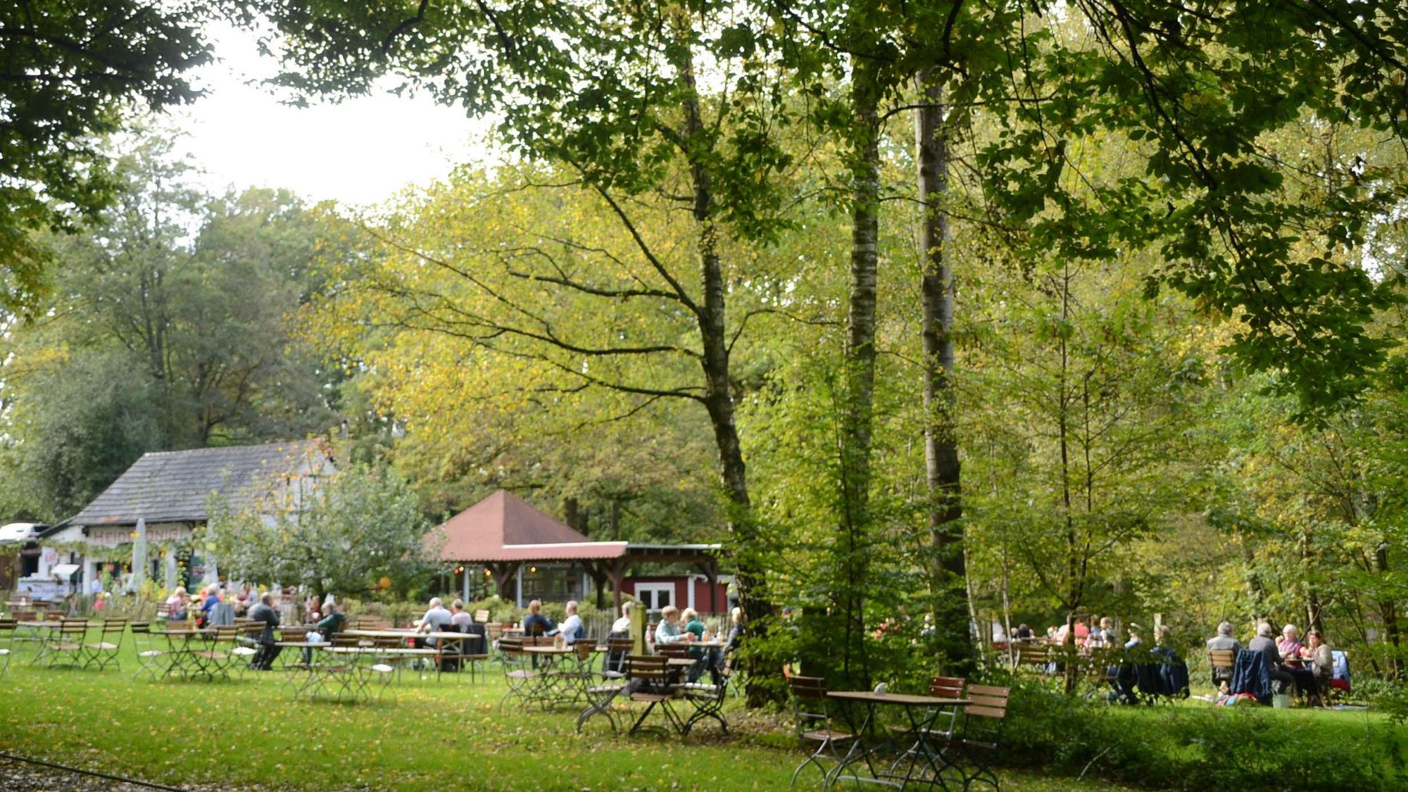 Ein Lokal mit Ausschank auf einer großen Wiese unter hohen Bäumen.