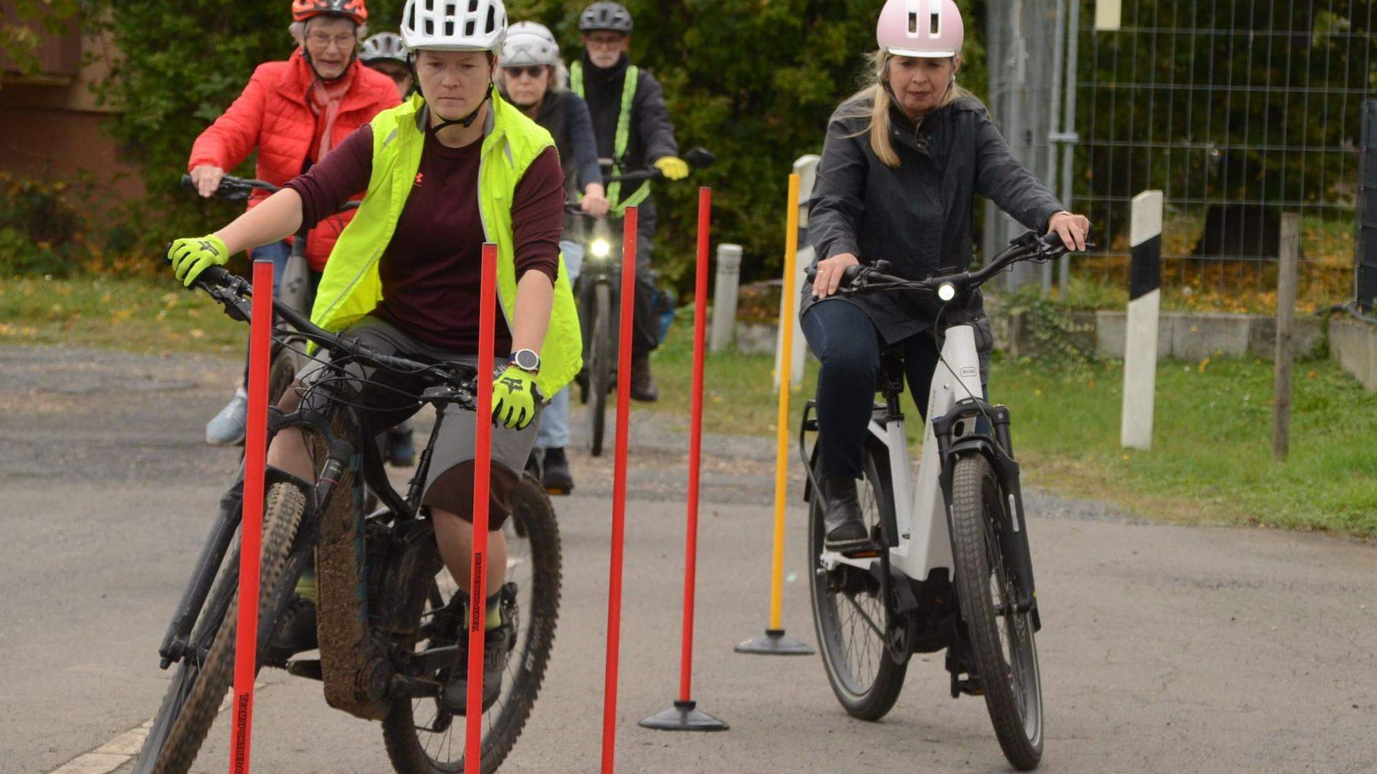 Frauen mit Pedelecfahrrädern fahren durch einen Stangenparcours.