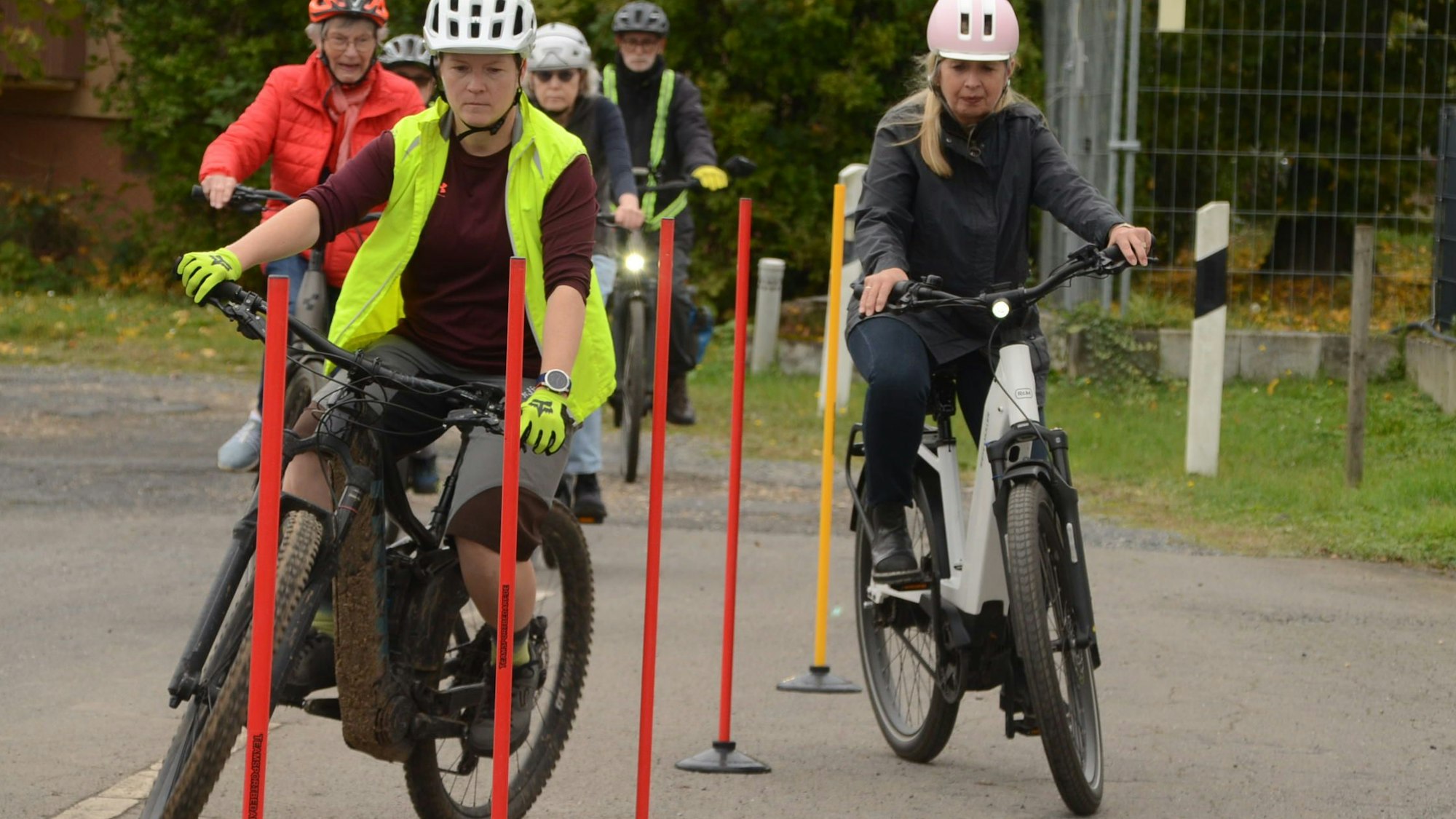 Frauen mit Pedelecfahrrädern fahren durch einen Stangenparcours.