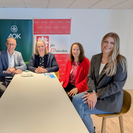 Berit Lamche-Fortouna (AOK), Helmut Schneider (Regionaldirektor AOK Bonn/Rhein-Sieg-Kreis/Euskirchen), Maria Surges-Brilon (Caritas), Dorothee Koch (Diplompädagogin) und Gianna Winkle (Sozialpädagogin) sitzen um einen Tisch.