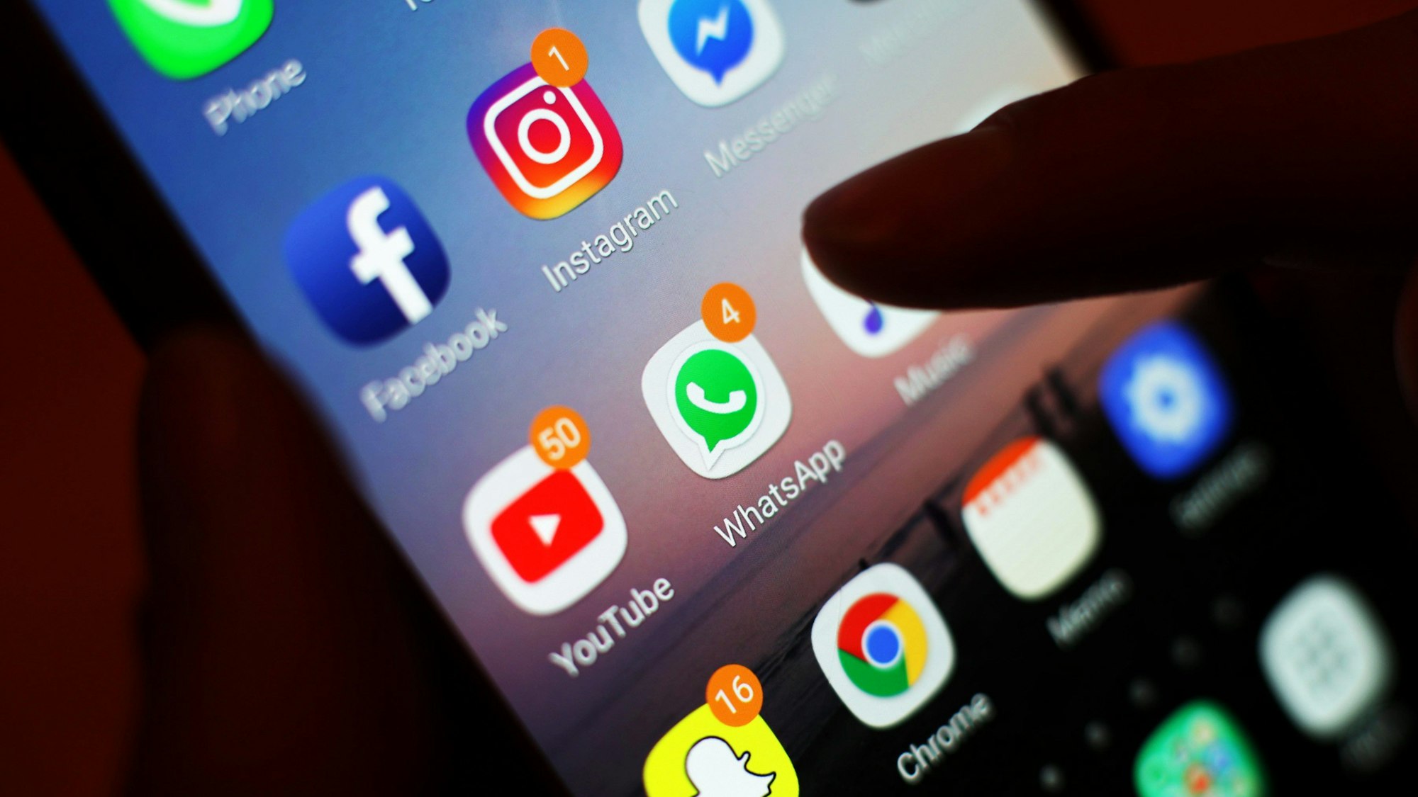 Ein Blick auf ein Handy mit den verschiedenen Social Media Apps, wie Facebook, Instagram, WhatsApp.