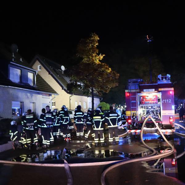 Dutzende Feuerwehrleute stehen auf einer Straße.
