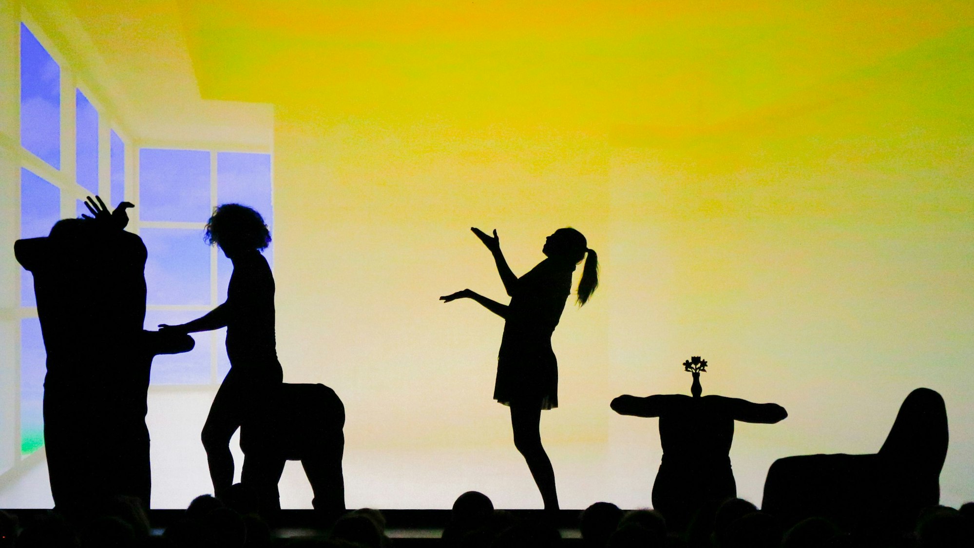 Eine Schattentheater-Szene: Ein Mann spiel Klavier, rechts davon stehen eine Frau, ein Tisch und ein Sessel.