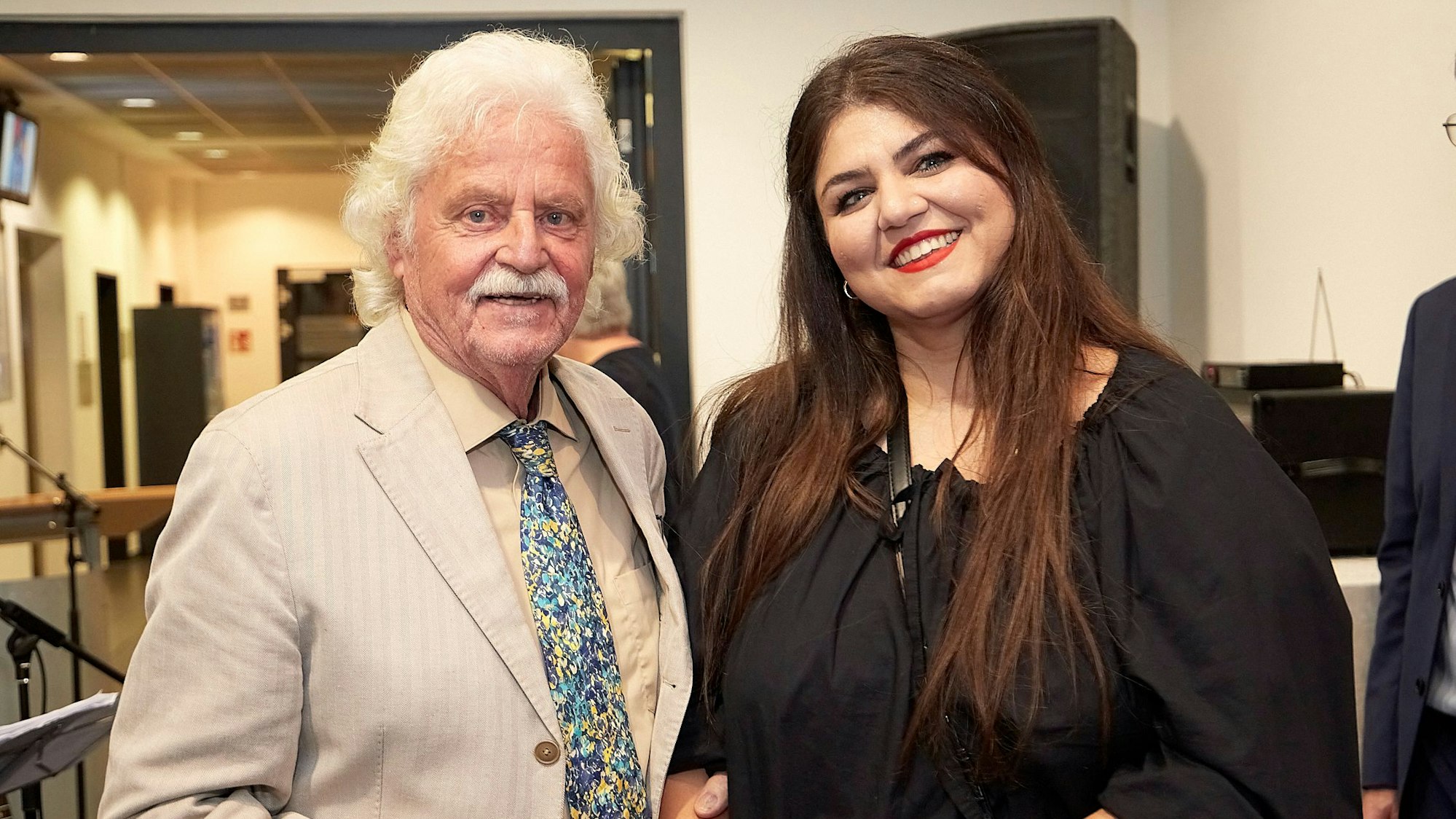 Kurator Franz Kruse und die Künstlerin Sara Sheiky stehen bei der Vernissage ihrer Ausstellung in einem Flur des Rathauses in Mechernich.