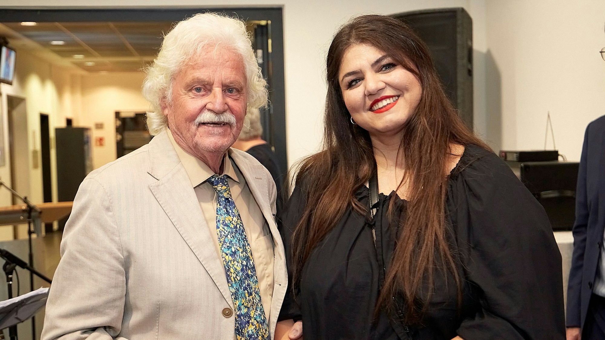 Kurator Franz Kruse und die Künstlerin Sara Sheiky stehen bei der Vernissage ihrer Ausstellung in einem Flur des Rathauses in Mechernich.
