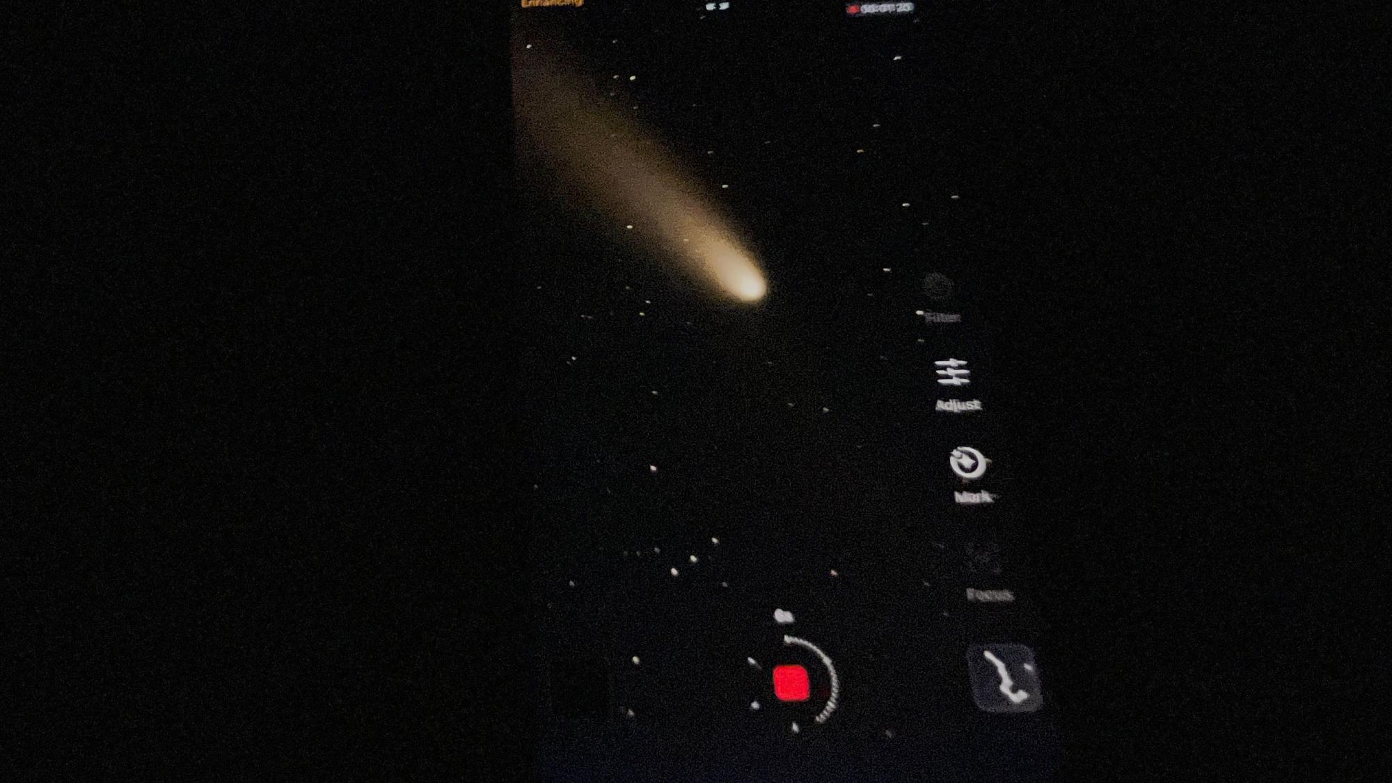 Auf einem Handy-Bild-Schirm ist der Komet zu sehen.