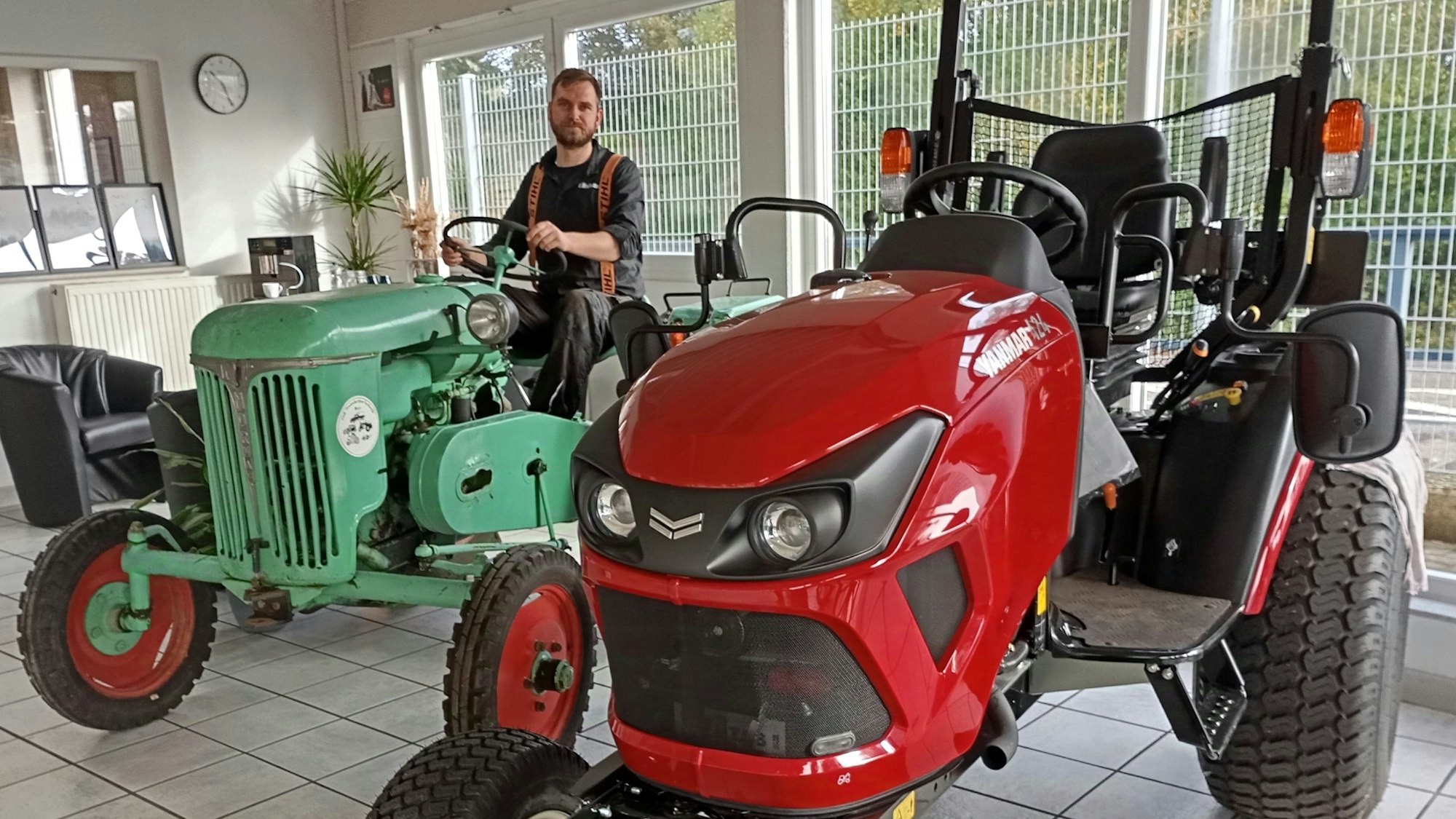 Ein Mann sitzt auf einem Traktor, er lächelt in die Kamera.