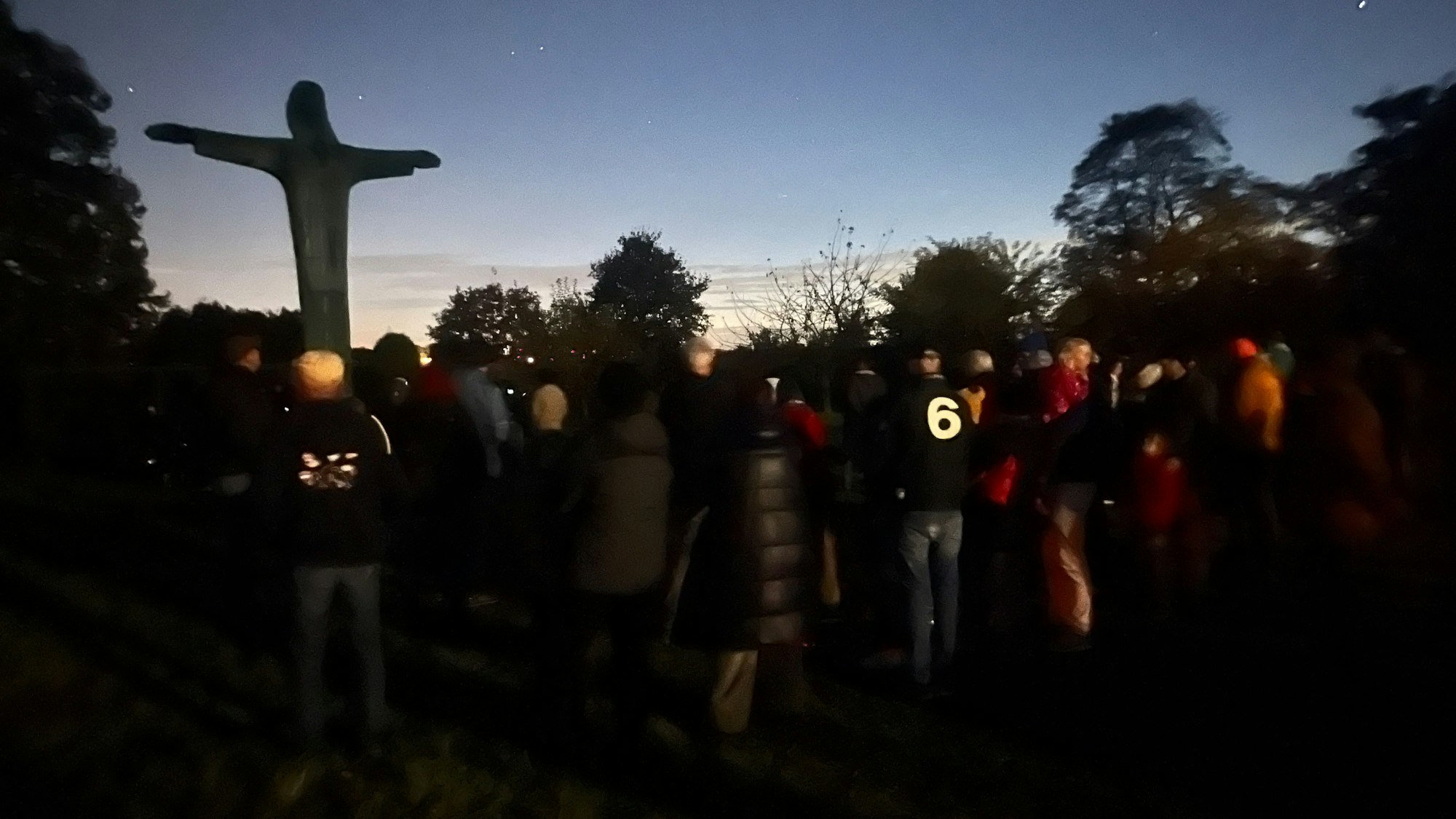 Menschen stehen vor einer Jesusstatue und schauen zu den Sternen am Himmel.