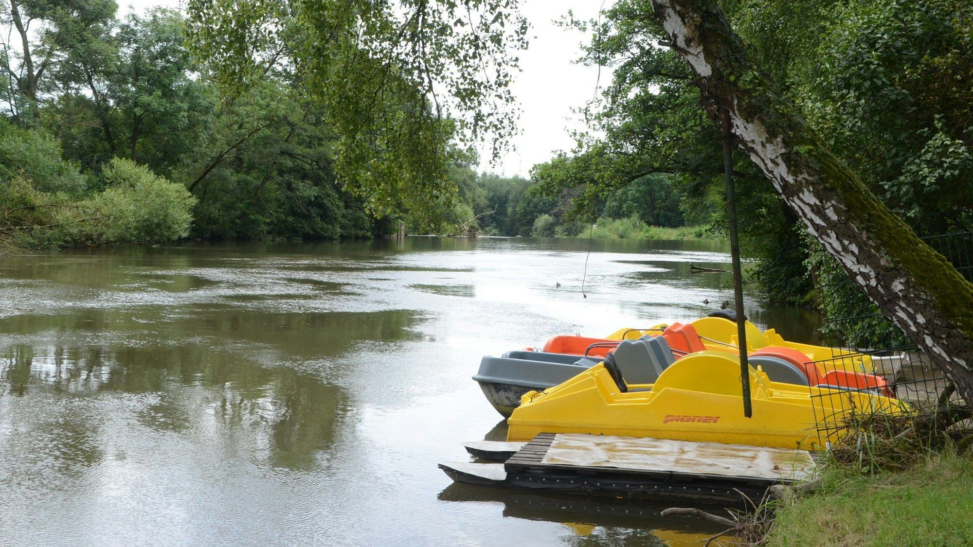Tretboote sind am Ufer eines Flusses festgemacht.