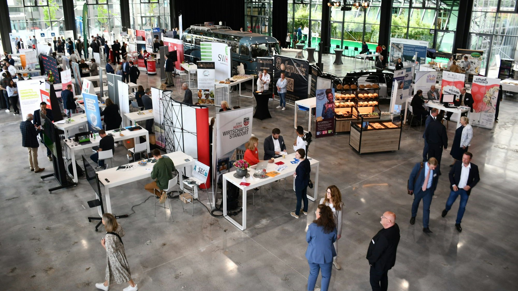 Zu sehen sind Stände und Menschen in einem Gebäude bei einer Veranstaltung.