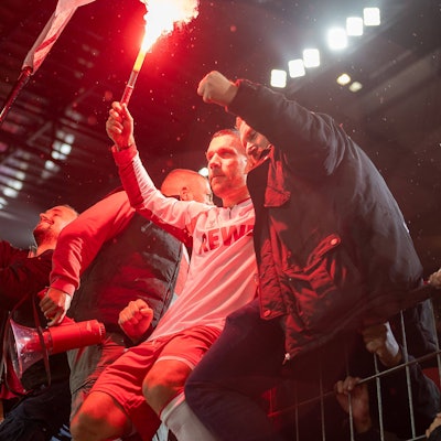 Lukas Podolski feiert mit einer Fackel in der Hand und seinen Fans.