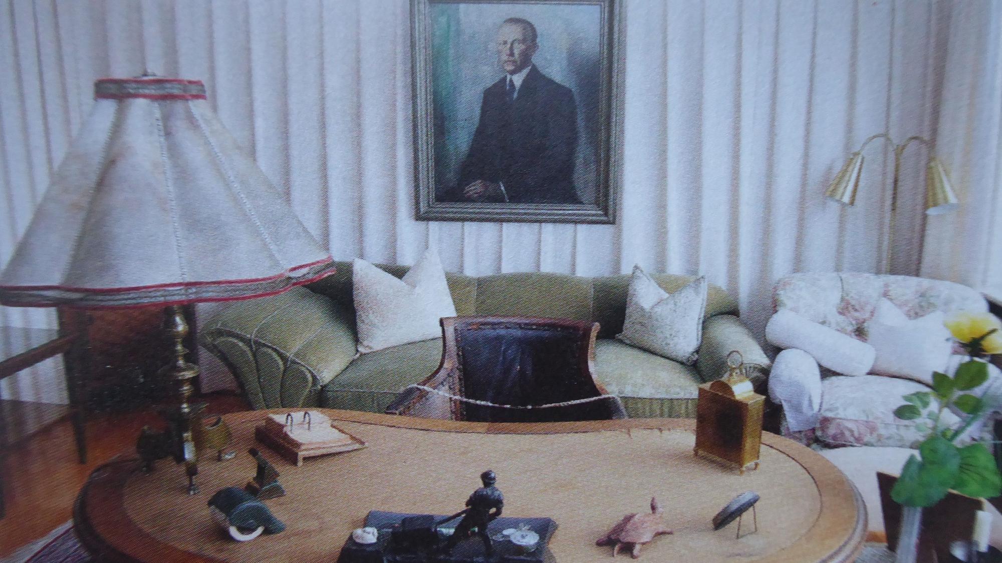 Blick in das Arbeitszimmer des ersten Bundeskanzlers Konrad
Adenauer mit einem Schreibtisch im Vordergrund und einem Sofa, einem Sessel und einem Porträtbild im Hintergrund.