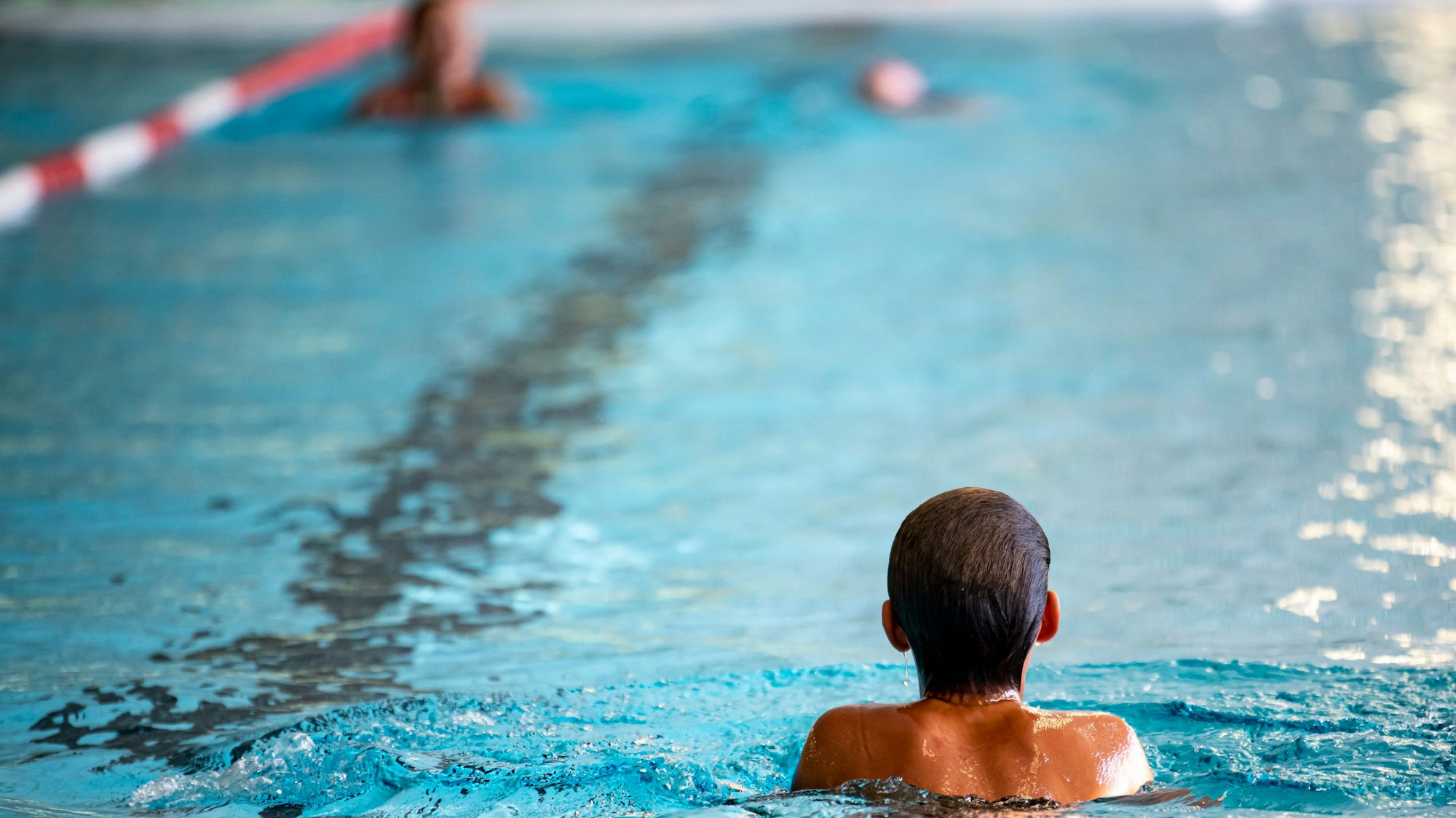 Ein Kind schwimmt in einem Hallenbad.