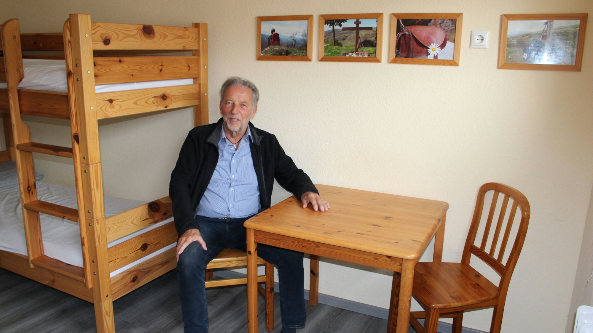 Ein älterer Herr sitzt an einem Tisch in einem Herbergszimmer.