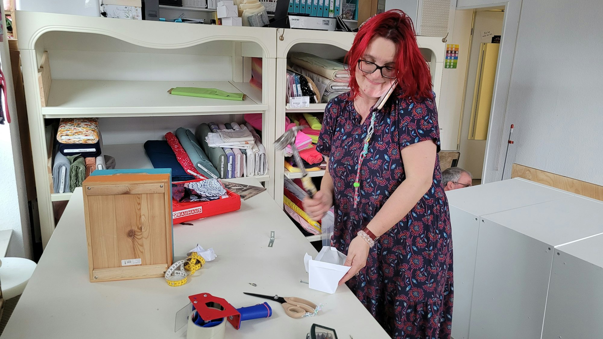 Eine Frau hat ein Handy am Ohr, sie räumt Werkzeug ein.