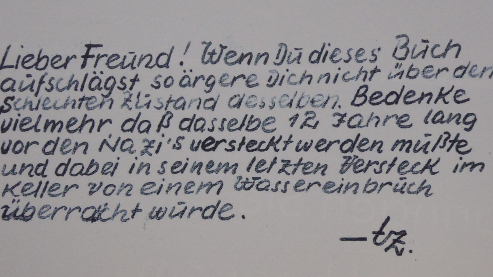 Eine handgeschriebene Mitteilung in acht Zeilen. Der Text lautet: Lieber Freund! Wenn du dieses Buch aufschlägst, so ärgere dich nicht über den schlechten Zustand desselben. Bedenke vielmehr, dass dasselbe zwölf Jahre lang vor den Nazis versteckt werden musste und dabei in seinem letzten Versteck im Keller von einem Wassereinbruch überrascht wurde.
