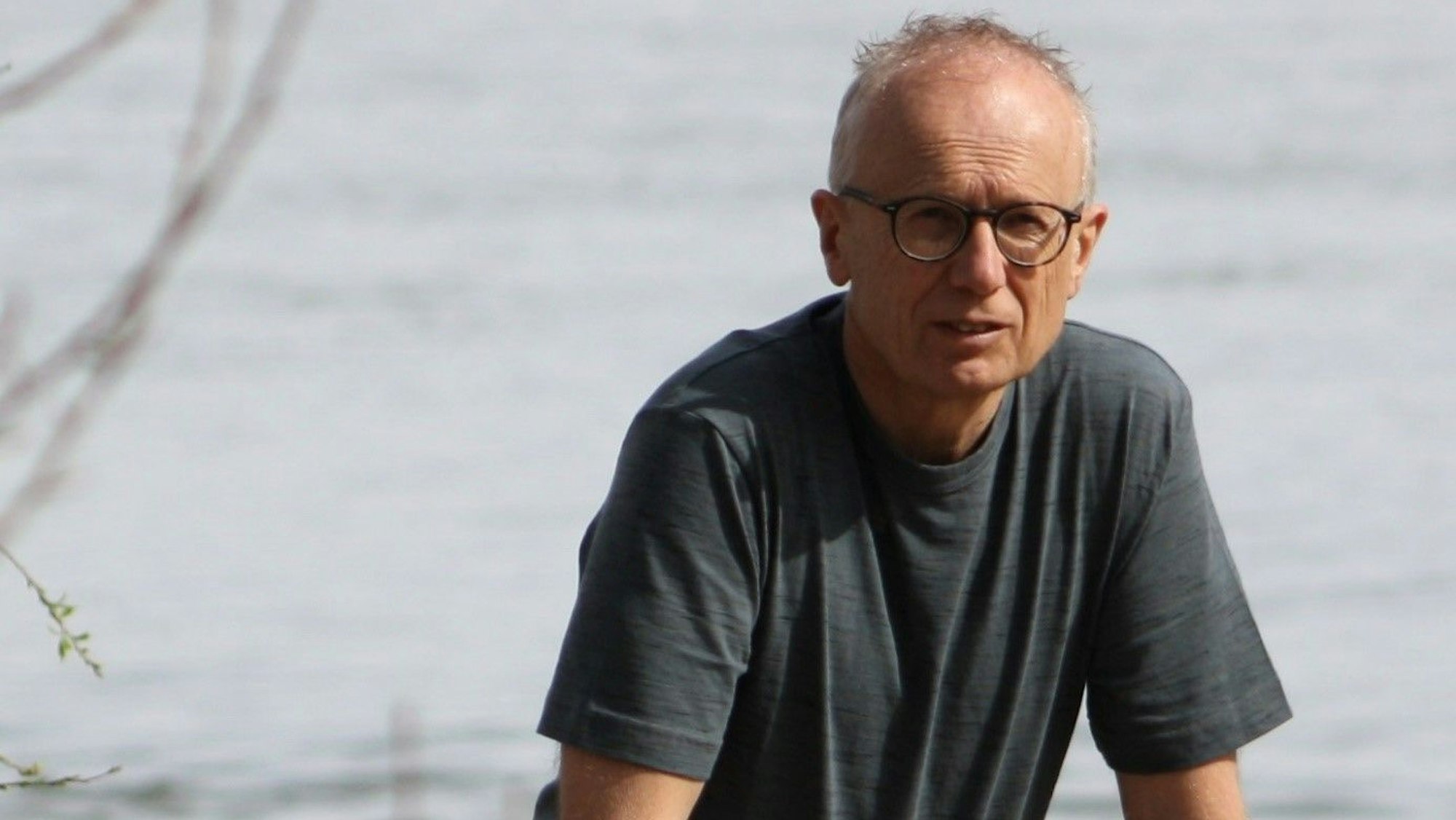 Zu sehen ist ein Mann vor einem See.