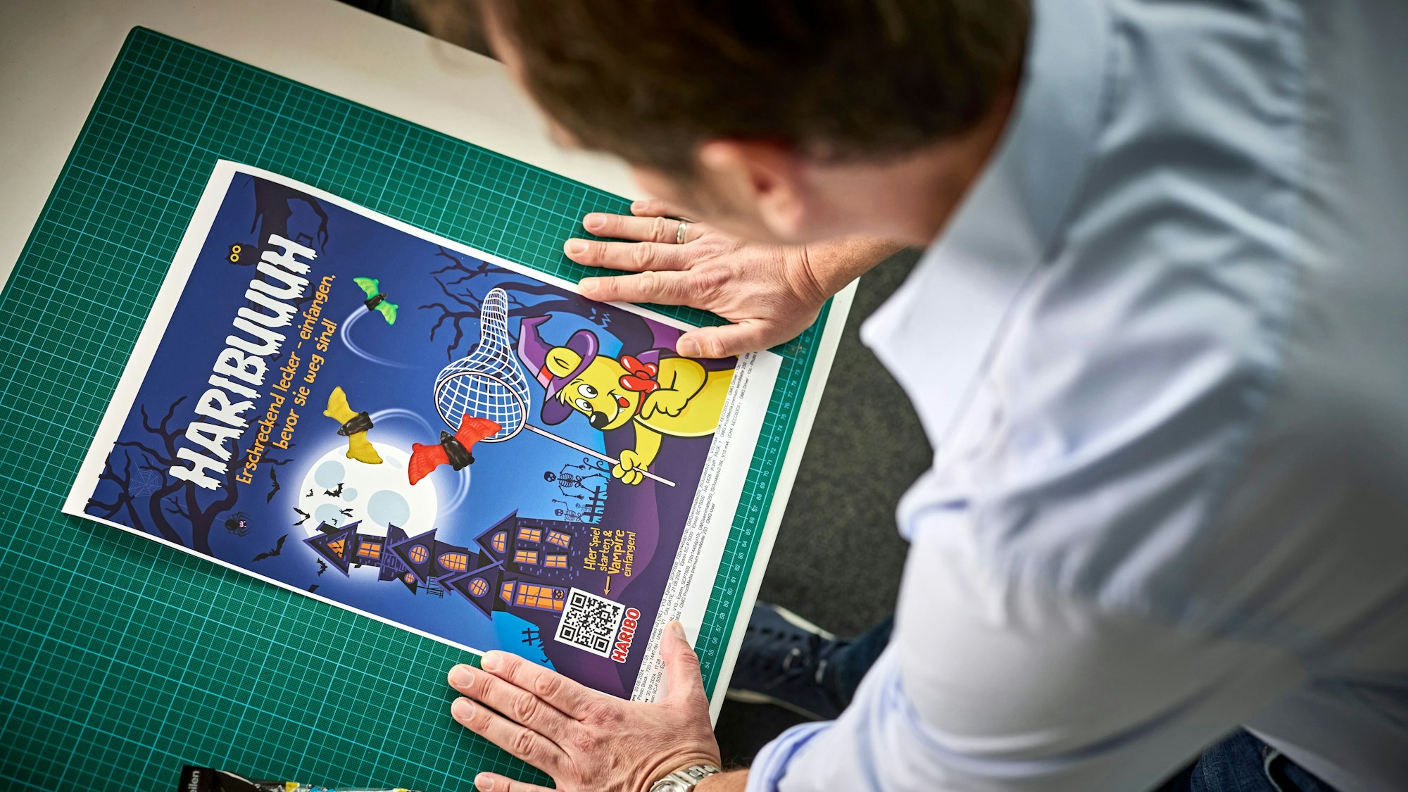 Konrad Lohrmann lehnt über dem Halloween-Poster, mithilfe dessen Fans auf virtuelle Vampirjagd gehen können.