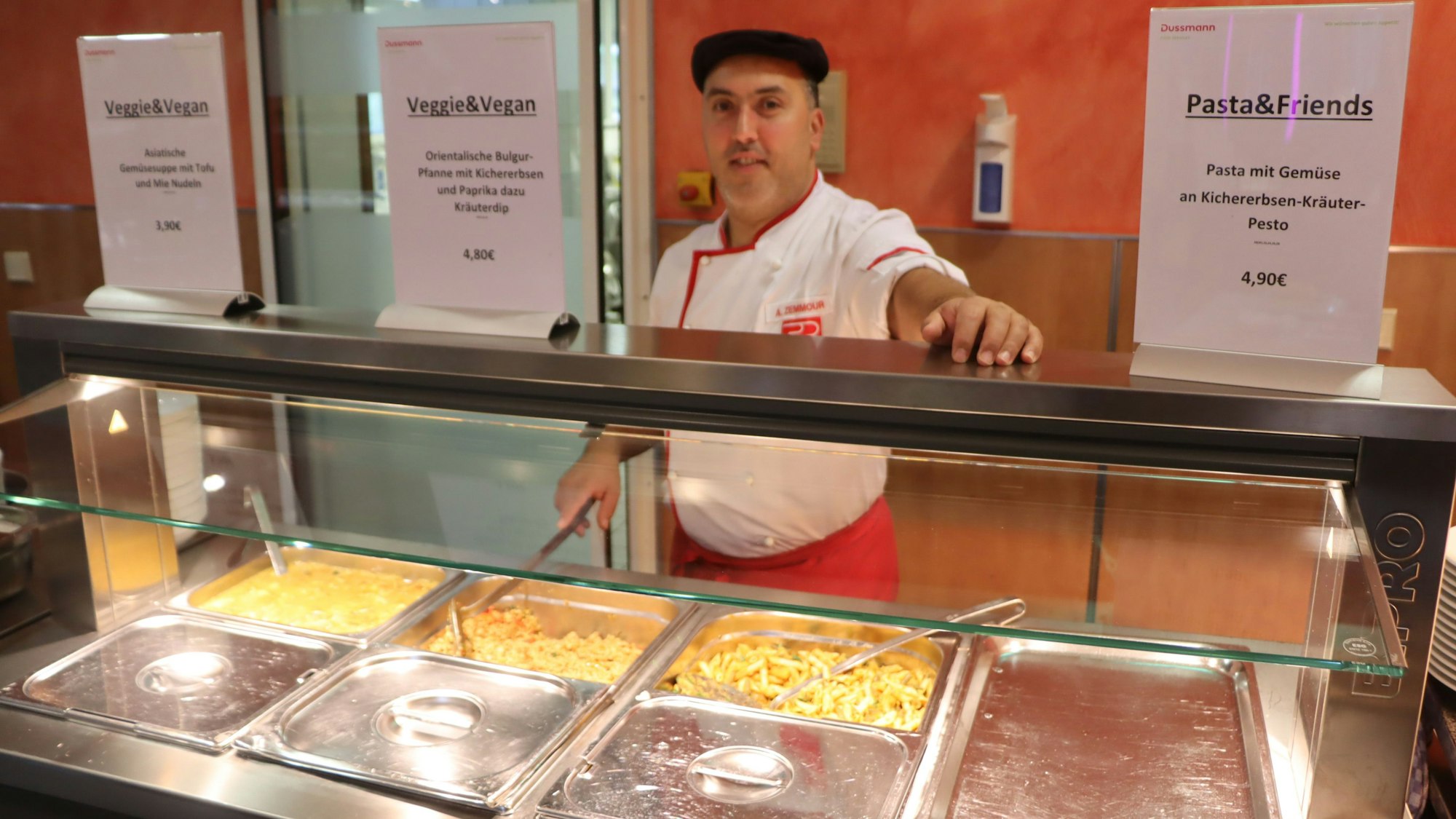 Ein Mann steht an einer Essensausgabe.