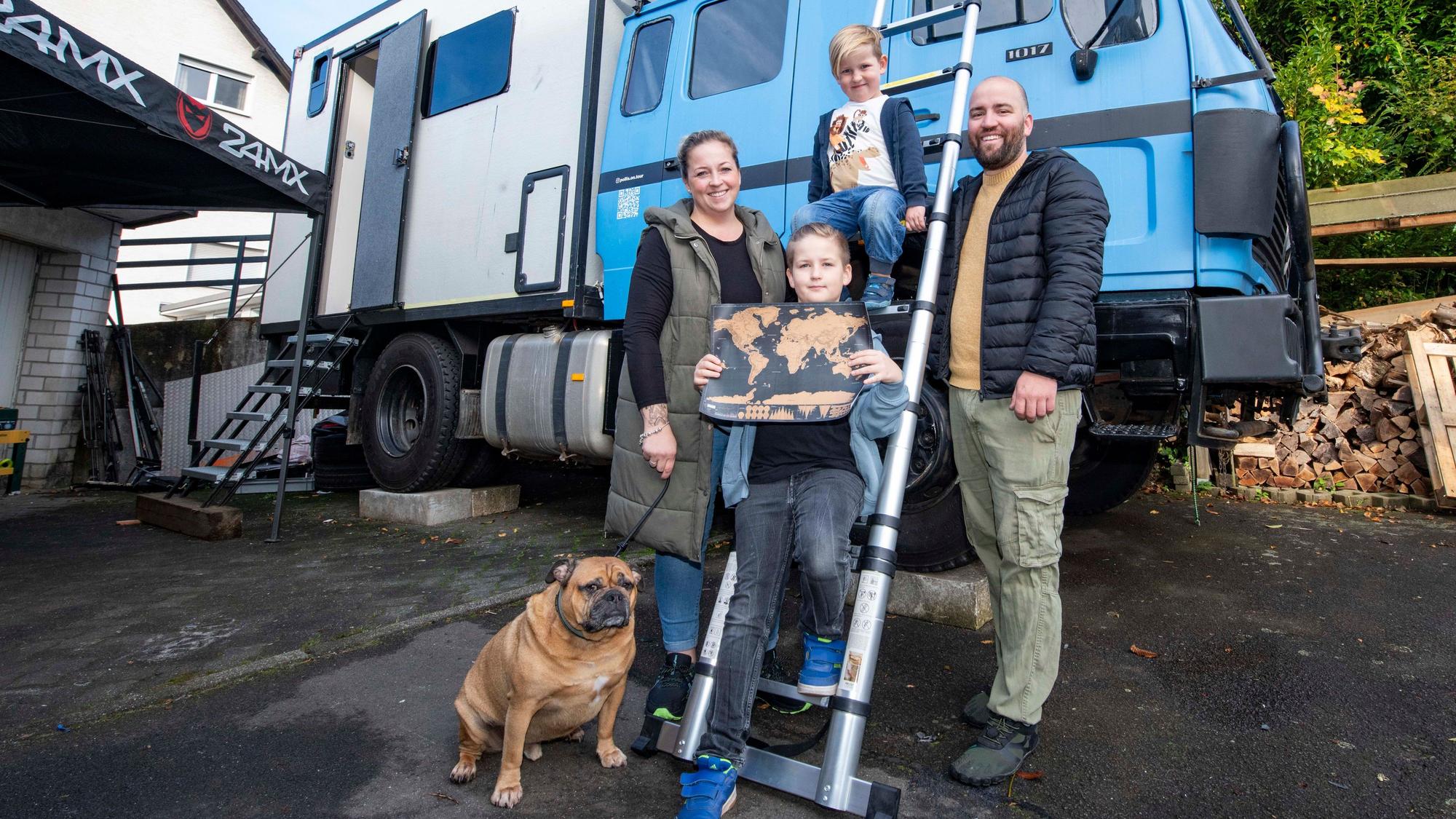 Familie Pollkläsener aus Gummersbach steht vor einem Expeditionsmobil mit hellblauem Führerhaus.